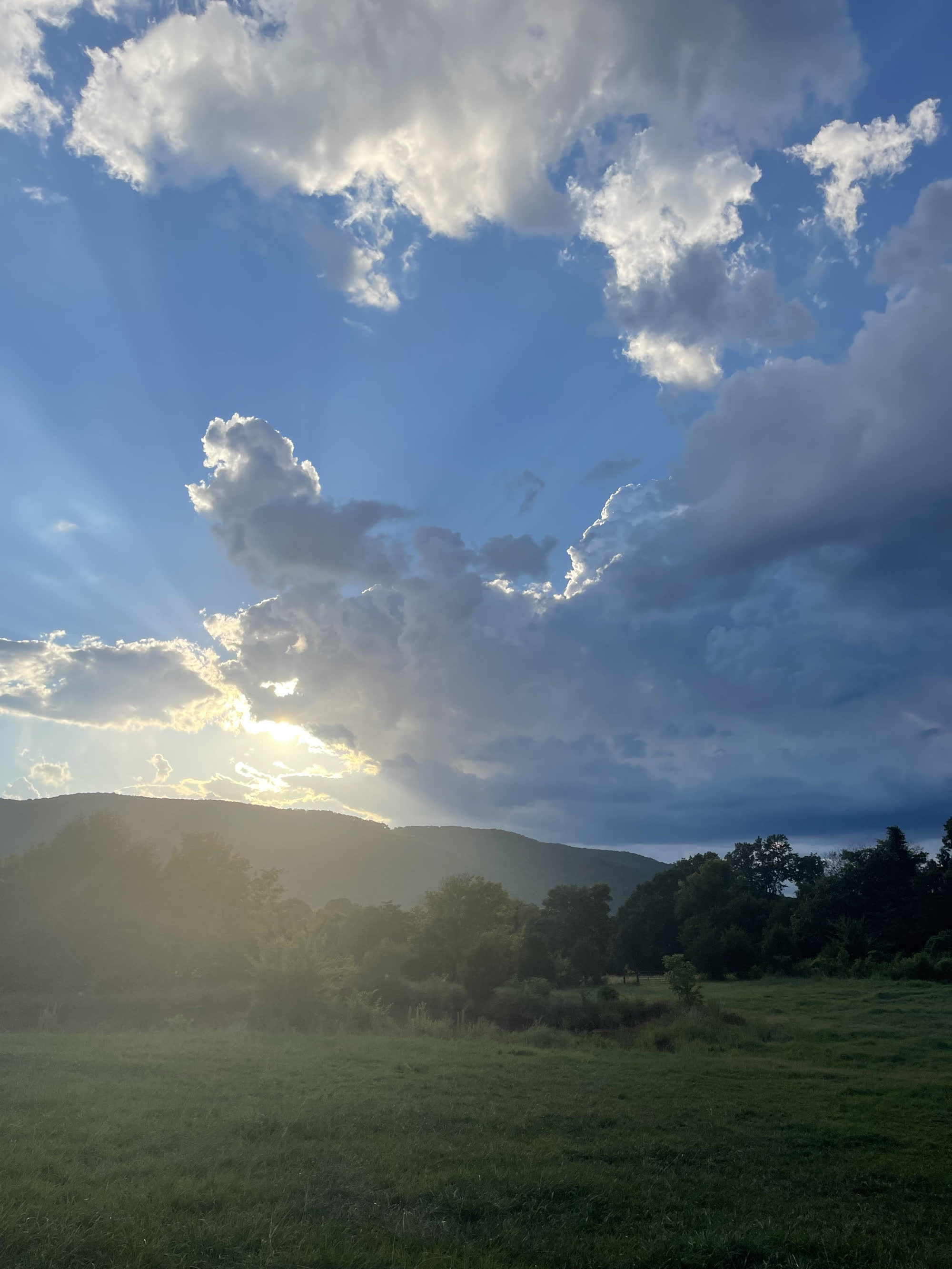 Dramatic cumulus clouds with sunbeams piercing through, over the valley
